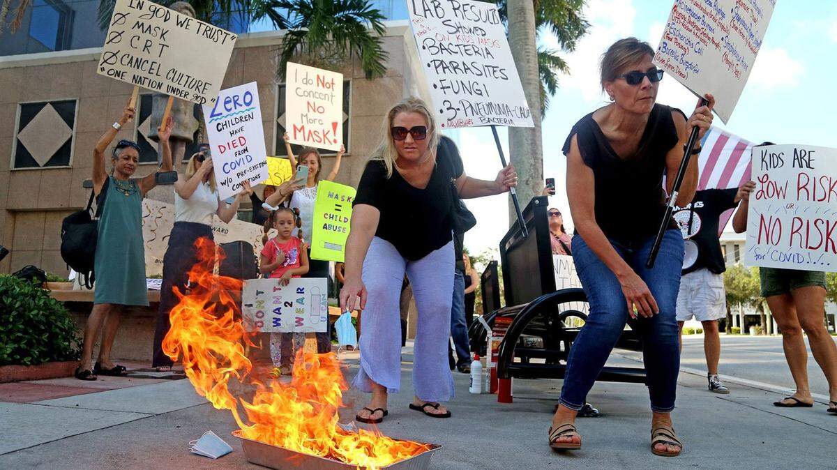 Heather Tanner of Cooper City and Kim Castrillon of Plantation burn masks in front of the Broward school board building over the summer. The Broward School Board is convening an emergency meeting on Friday, Dec. 31, 2021, to discuss masks given the surging COVID cases in Florida. The masks would not be for students, but for faculty, staff and visitors.
