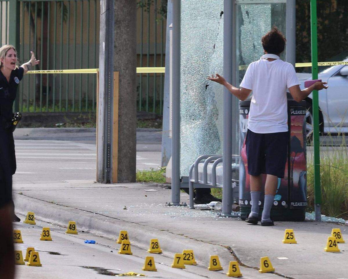 Un policía de Miami da una severa advertencia a un peatón después que el hombre ingresara en la escena del crimen donde cuatro personas recibieron disparos, dos de ellas fallecidas, tras un tiroteo ocurrido la madrugada del lunes 16 de junio de 2025 en Miami.