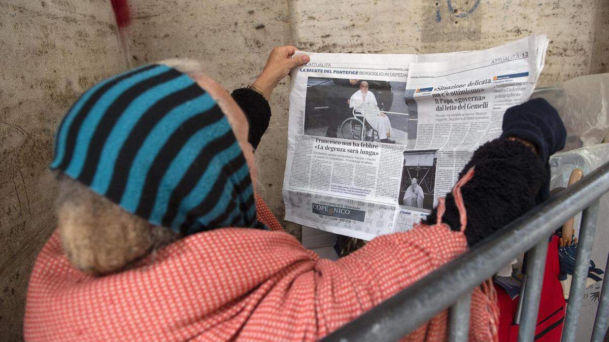 Una mujer sin hogar lee un periódico que informa sobre la hospitalización del Santo Padre cerca de la Plaza de San Pedro en El Vaticano. 