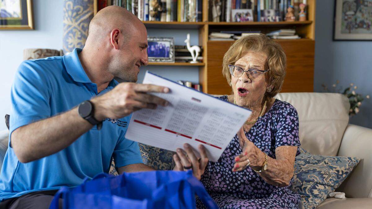 Zach Goodstat, administrador de atención del Programa de Asistencia a Sobrevivientes del Holocausto de Goodman Jewish Family Services, le entrega a Ruth Di Stefano, sobreviviente del Holocausto de 97 años, un calendario en su casa el viernes 19 de septiembre de 2025 en Fort Lauderdale, Florida.