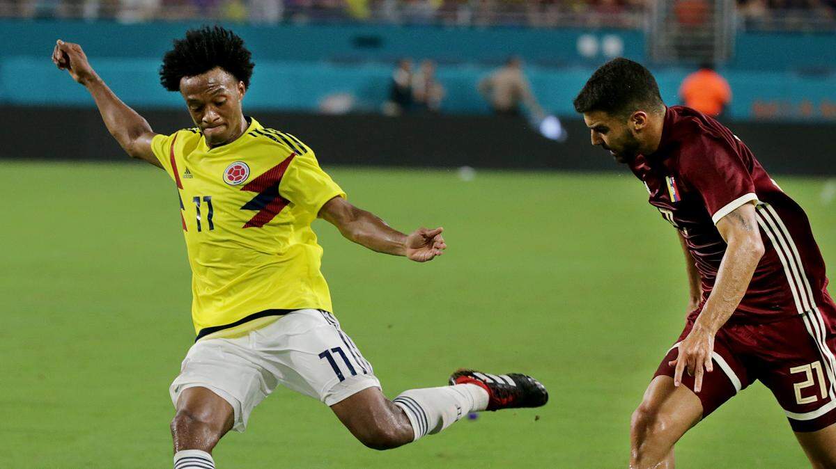 El mediocampista colombiano Juan Guillermo Cuadrado patea el balón ante la marca del venezolano Angel González, en el partido amistoso efectuado el 7 de septiembre de 2018 en el Hard Rock Stadium, en Miami Garden, Florida.