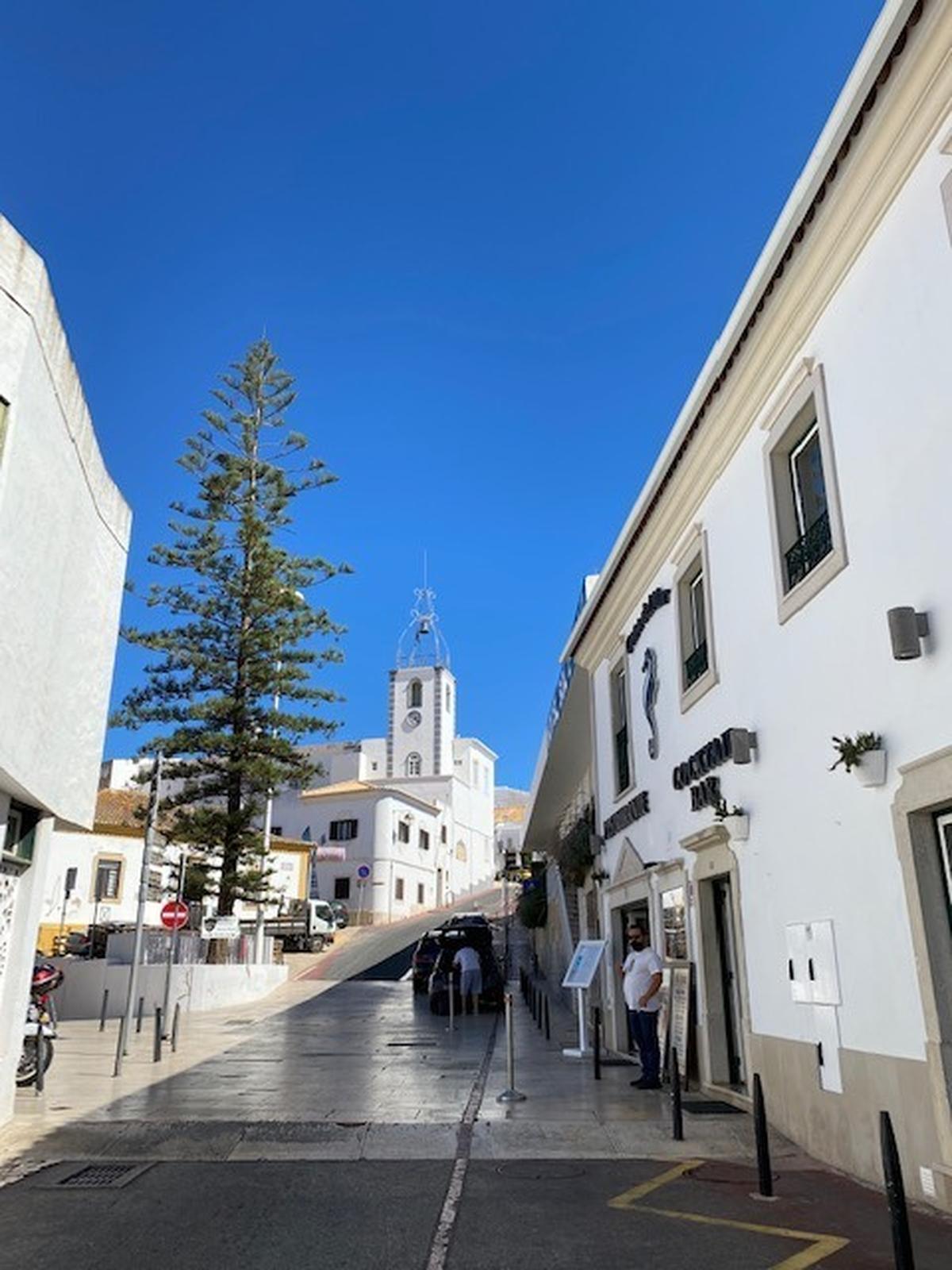 Calle comercial e iglesia en Albufeira, centro turístico de Algarve.