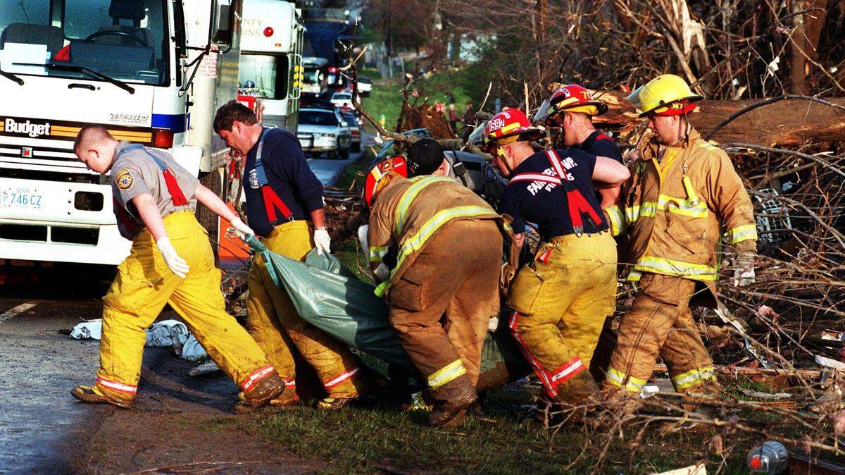 Los bomberos retiran una de las dos víctimas encontradas entre los escombros del tornado del 9 de abril de 1999 en Cornell Road, cerca de Sycamore High School en Montgomery.