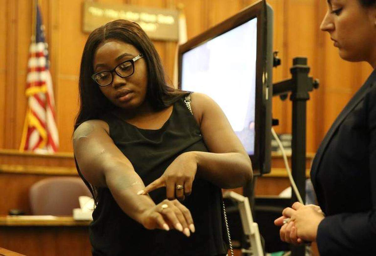 Curtina Gray se para frente al jurado y muestra las cicatrices en su brazo derecho causadas por las puñaladas luego del ataque del 6 de agosto de 2012 del ex novio de su madre, Alphonso Jerard Lucas.