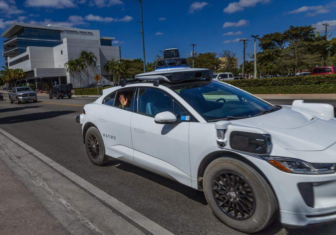 El reportero del Miami Herald, Michael Butler, saluda desde la ventana de un coche autónomo Waymo en la calle 8 del suroeste mientras el vehículo autónomo se dirige al Brickell City Center.