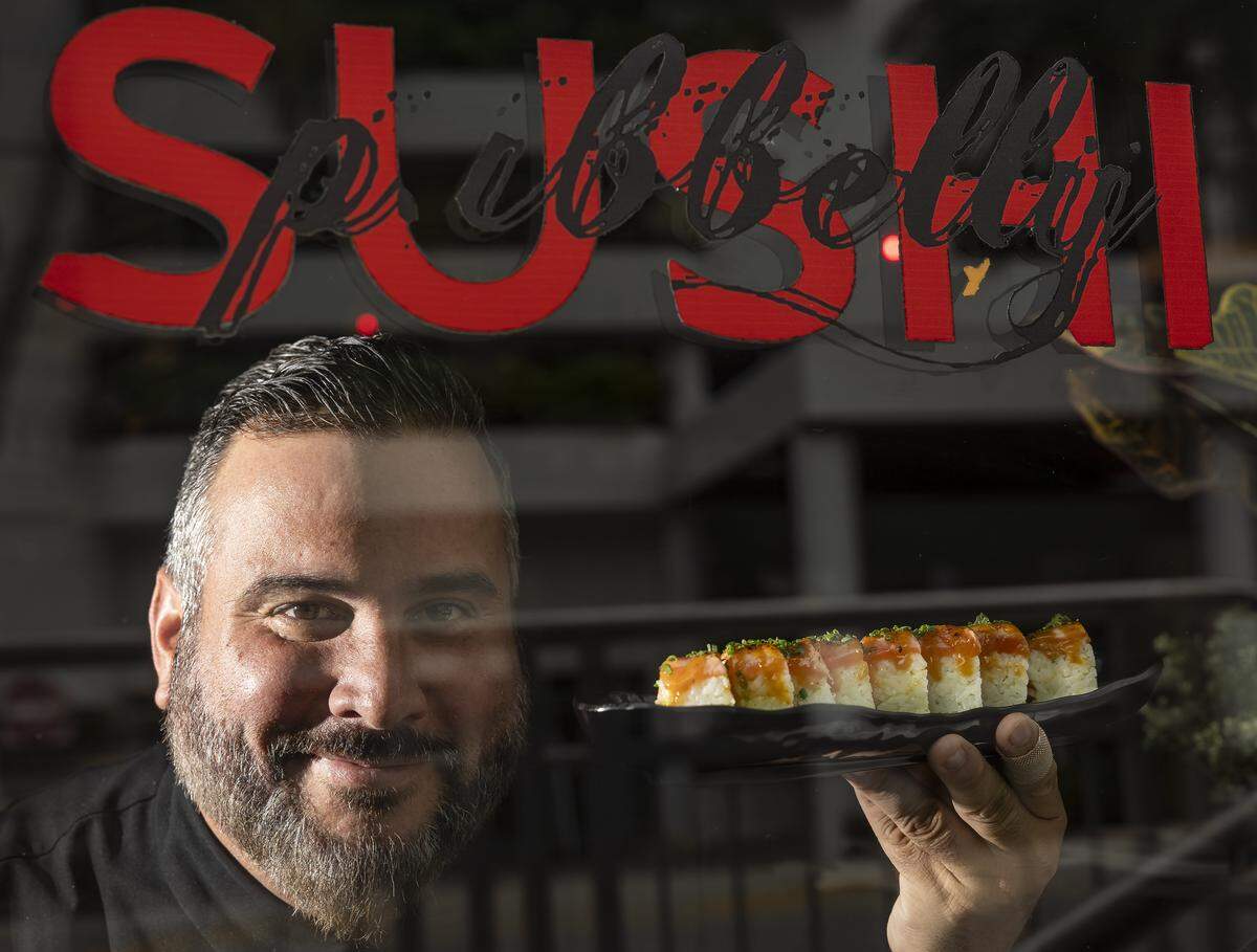 El chef José Mendín sostiene un rollo de sake aburi que consiste en kanikama, salmón sellado, yuzu miso, aceite de trufa y shichimi.