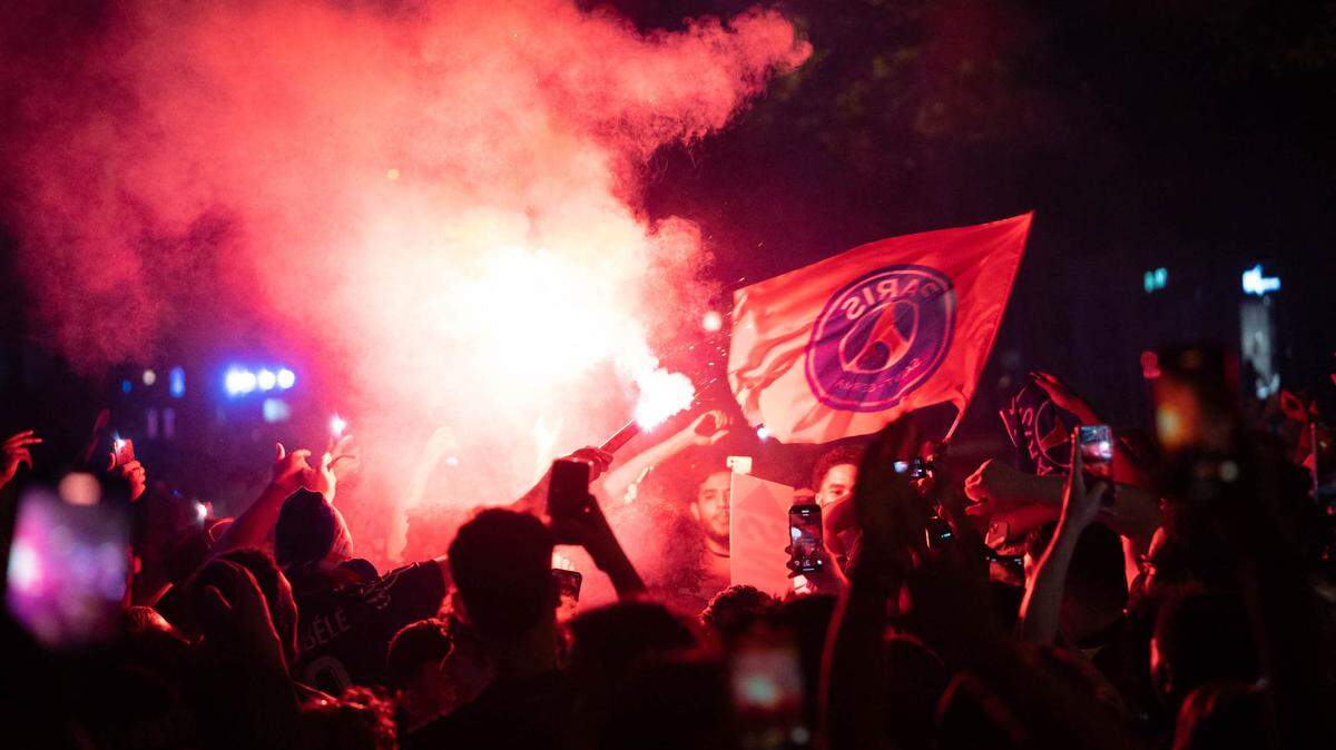 Los hinchas del Paris Saint-Germain (PSG) festejan con bengalas en París la madrugada del domingo 1 de junio de 2025, durante las celebraciones tras su victoria por 5-0 en la final de la UEFA Champions League contra el Inter de Milán celebrada en Múnich.