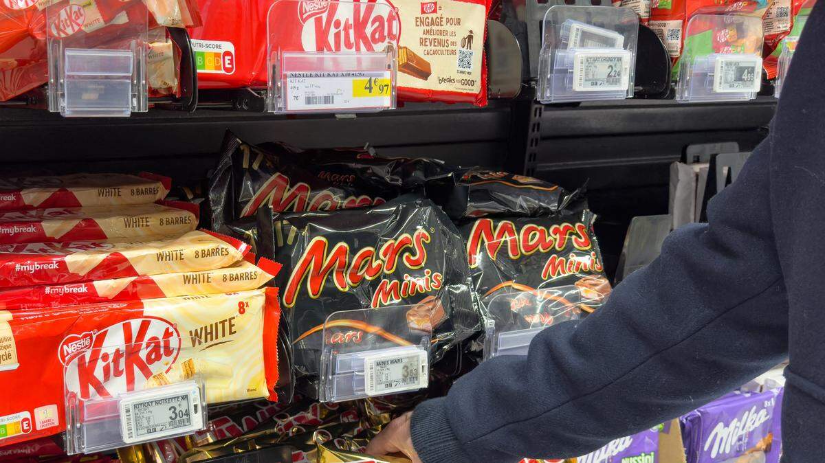 Un hombre en el pasillo de dulces, rodeado de barras de chocolate y otros productos como KitKat, Lion, Mars, Kinder Bueno, Twix, Balisto, Milka, entre otros, en un supermercado de Saint-Paul-lès-Dax, en la región de Las Landas, Nueva Aquitania, Francia, el 16 de enero de 2026.
