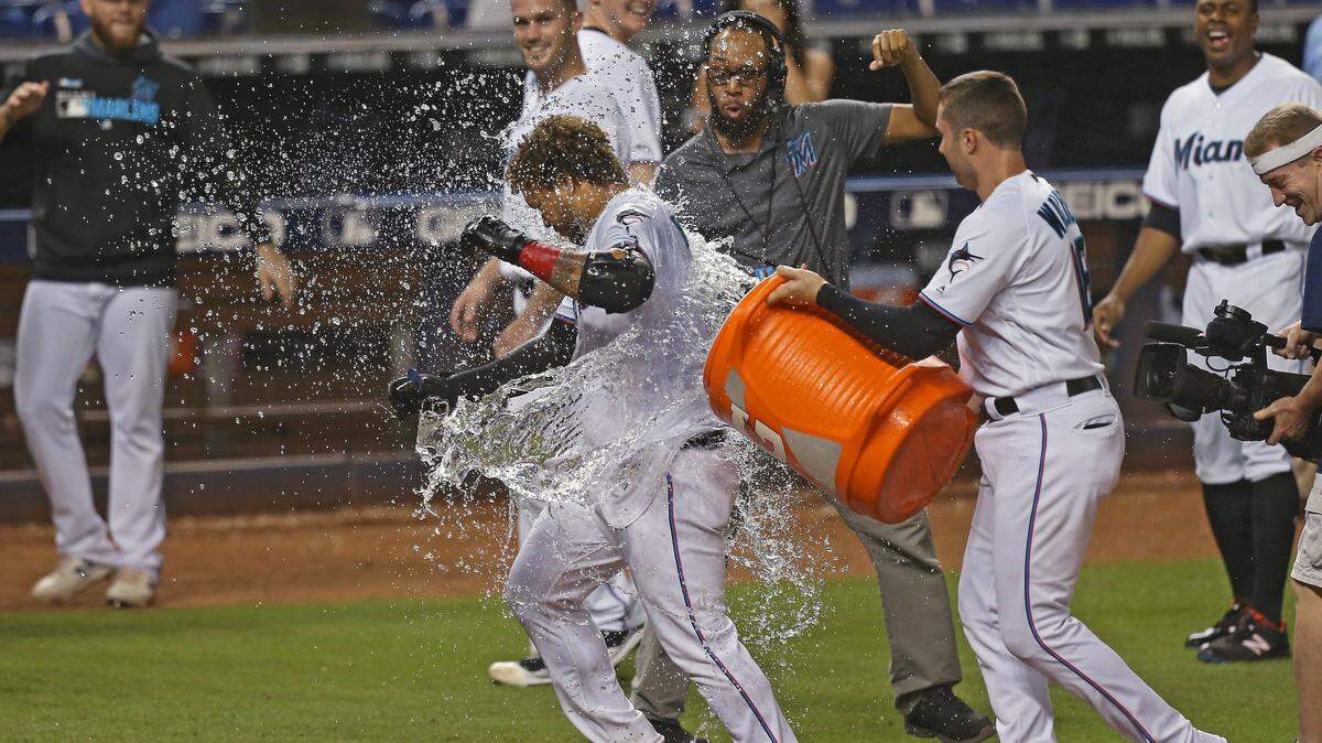 El jardinero de los Marlins Harold Ramírez recibe un baño de agua de sus compañeros de equipo tras pegar el jonrón que decidió la victoria 4-3 ante los Rojos en el inning 12, el 29 de agosto de 2019 en Miami.