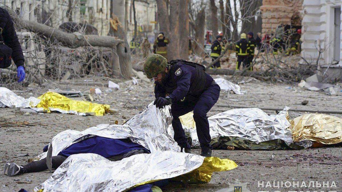 Un policía ucranio rodeado de cadáveres tapados con mantas. Según informó el Servicio Estatal de Emergencias de Ucrania (DSNS) en su cuenta de Telegram, en el ataque fallecieron al menos 34 personas, entre ellas dos niños, y otras 117 resultaron heridas, incluidos 15 niños.