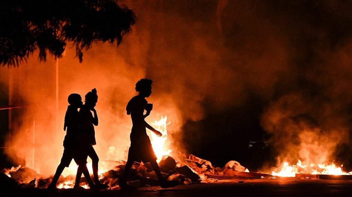 La gente pasa junto a un incendio provocado por manifestantes durante una protesta contra la falta de energía y los apagones en el barrio de Lawton en La Habana el 14 de mayo de 2026. Cuba culpó a Estados Unidos por la situación “particularmente tensa” en su red eléctrica, ya que el este del país se vio afectado por otro corte de energía generalizado el 14 de mayo de 2026.