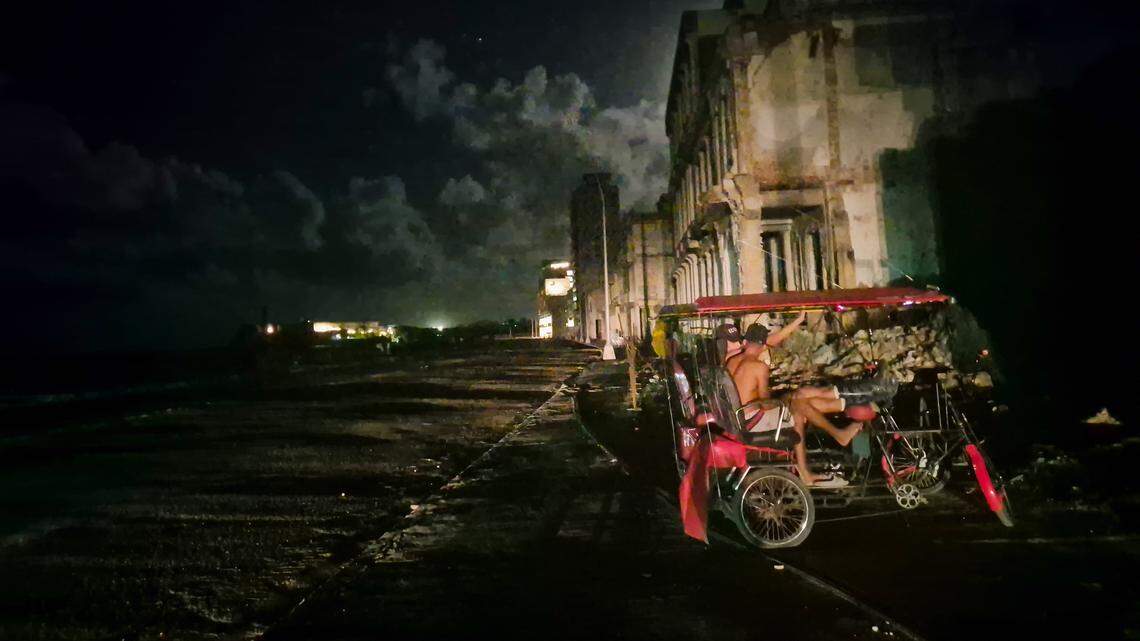 Two men sitting on their “bicitaxis” talk in Havana during Cuba’s third consecutive blackout on Oct. 20.