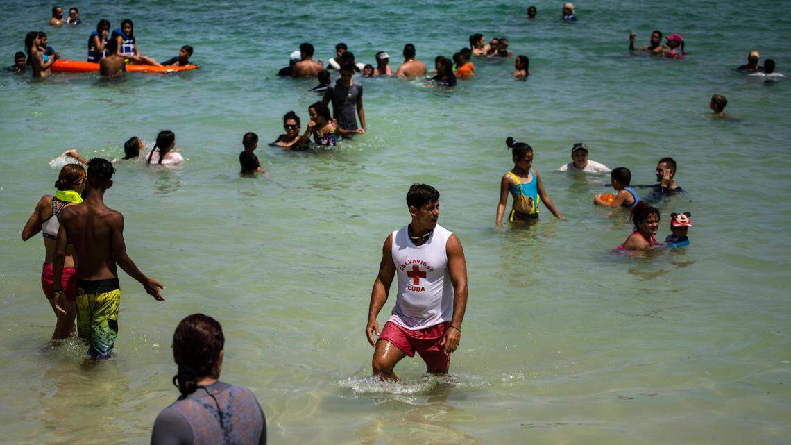 People wade in shallow waters at Playa del Salado in Caimito, Artemisa province, Cuba, Wednesday, July 15, 2020. Covid cases have climbed in Artemisa in recent weeks.