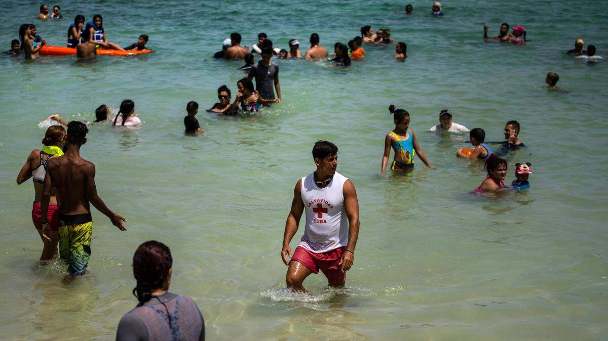 People wade in shallow waters at Playa del Salado in Caimito, Artemisa province, Cuba, Wednesday, July 15, 2020. Covid cases have climbed in Artemisa in recent weeks.