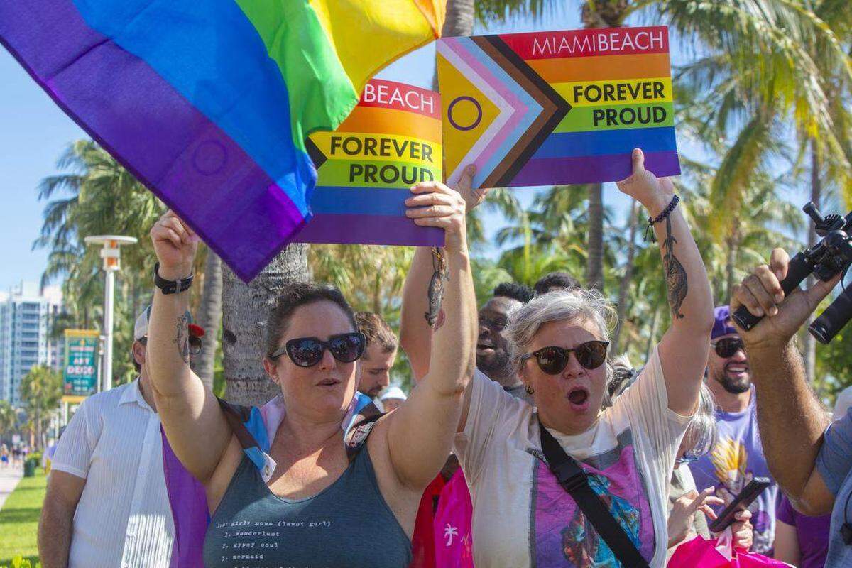 Adriana May y Cynthia Ordaz se reúnen con otros manifestantes que portaban banderas arcoíris y carteles con las leyendas “Miami Beach Orgulloso por Siempre” y “No Será Borrado” durante la Marcha Orgulloso por Siempre en Ocean Drive, Miami Beach, Florida, el domingo 31 de agosto de 2025. La marcha se realizó tras la orden de las autoridades estatales de eliminar el cruce peatonal del Orgullo LGBTQ de la ciudad.