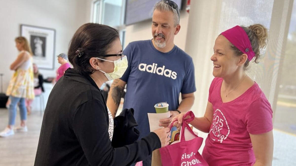 Rosemary Carrera (der.), fundadora y directora ejecutiva de 305 Pink Pack y sobreviviente de cáncer, ofrece una bolsa con productos para ayudar en el tratamiento y la recuperación del cáncer. Su fundación apoya a mujeres del sur de la Florida en tratamiento de cáncer con servicios gratuitos como transporte, cuidado de niños y asistencia con alimentos.