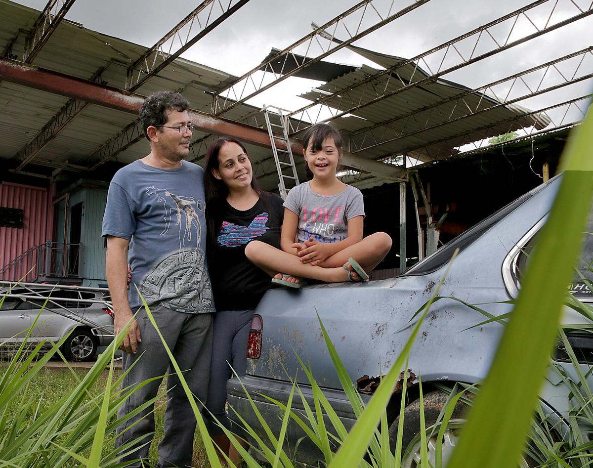 Yesenia Santiago y su esposo Roberto Colón con la hija de ambos, Marylee, de 10 años, quien sufre del síndrome de Down, afuera de la casa de la familia en Añasco, Puerto Rico. A la familia se le ha dificultado conseguir los servicios que Marylee necesita después del paso del huracán María en el 2017.