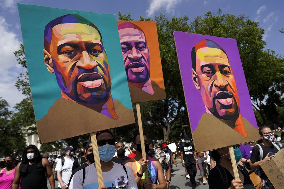 En esta foto de archivo del 28 de agosto de 2020, las personas llevan carteles con George Floyd mientras marchan desde el Monumento a Lincoln hasta el Monumento a Martin Luther King Jr. en Washington.