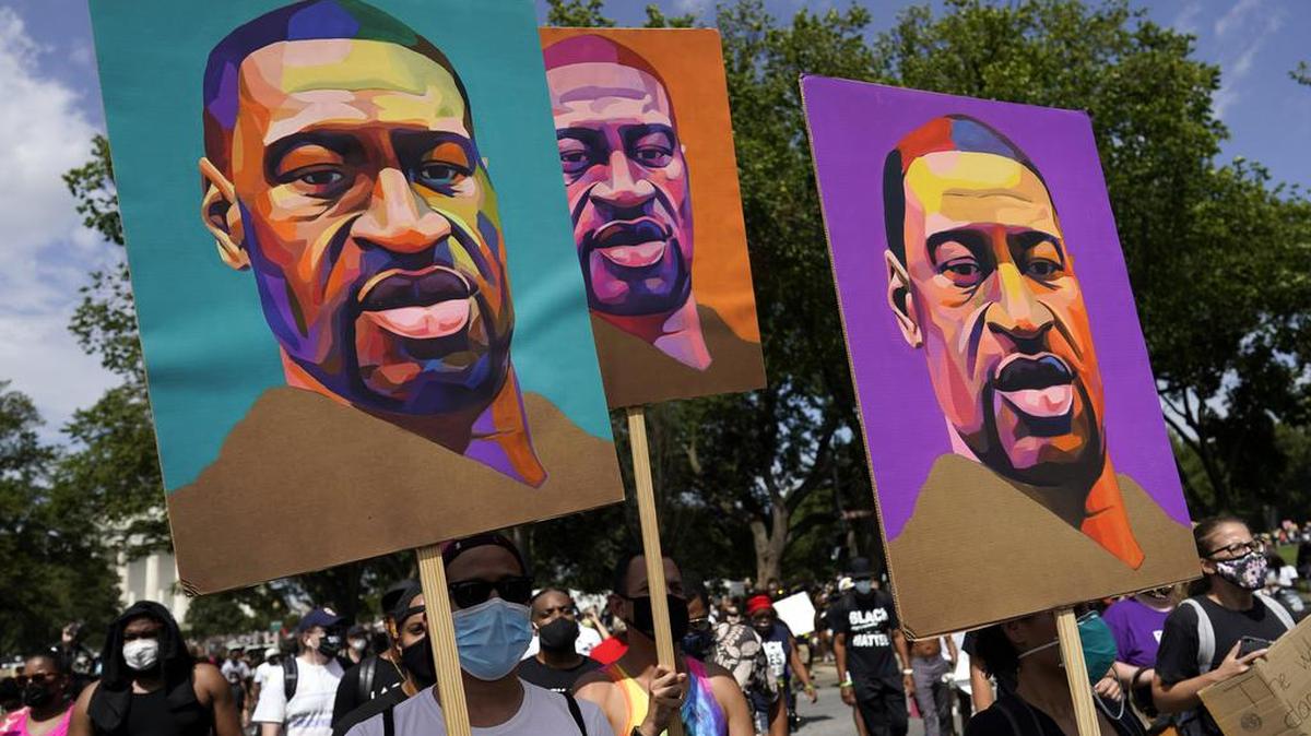En esta foto de archivo del 28 de agosto de 2020, varias personas llevan carteles con George Floyd mientras marchan desde el Monumento a Lincoln hasta el Monumento a Martin Luther King Jr. en Washington.