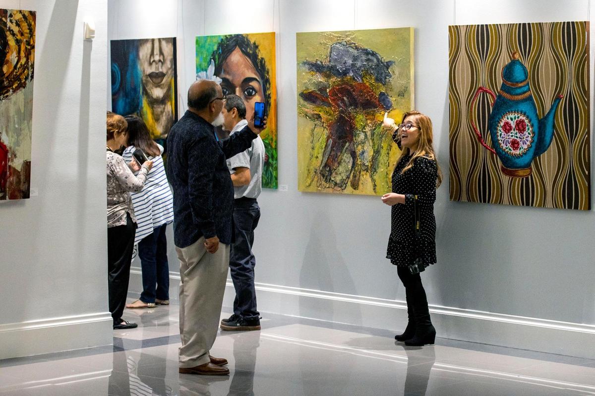 Los artistas Noel y Liz Nevado, de origen venezolano, se toman fotos con sus obras de arte durante la exhibición de artistas latinoamericanos en el Milander Center en Hialeah, Florida, viernes 30 de septiembre de 2022.
