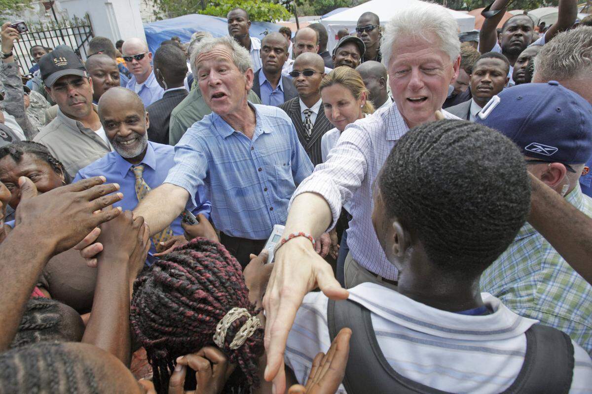 El entonces presidente haitiano René Préval camina con los ex presidentes estadounidenses George W. Bush y Bill Clinton, al tiempo que saludan a los haitianos en un campamento de desplazados por el terremoto en la Plaza Mosolee, junto al destruido palacio presidencial. Bush y Clinton copresidieron el Fondo Clinton Bush para Haití con el fin de recaudar fondos después del terremoto.