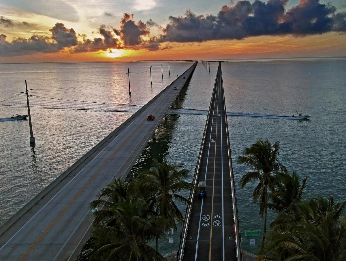 Este lunes 10 de enero de 2022, una foto aérea de un dron proporcionada por Florida Keys News Bureau muestra el puente Old Seven Mile listo para su reapertura el miércoles 12 de enero de 2022 a peatones, ciclistas, pescadores y visitantes de Pigeon Key (isla se muestra en la foto). El viejo puente originalmente era parte del Ferrocarril Over-Sea de los Cayos de Florida de Henry Flagler que se completó en 1912. El ferrocarril cesó sus operaciones en 1935 y se convirtió en una carretera que se inauguró en 1938. En 1982, se completó la construcción de un nuevo Puente de Siete Millas , detrás, que continúa transportando vehículos motorizados entre el sur de la Florida continental a lo largo de los Cayos hasta Cayo Hueso. (Andy Newman/Oficina de noticias de los Cayos de Florida vía AP)