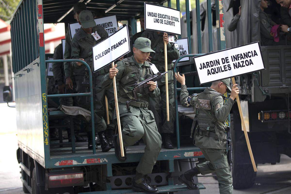 Foto del 15 de mayo del 2018 con soldados que llevan carteles con los nombres de las escuelas que funcionarán como centros de votación en Caracas.