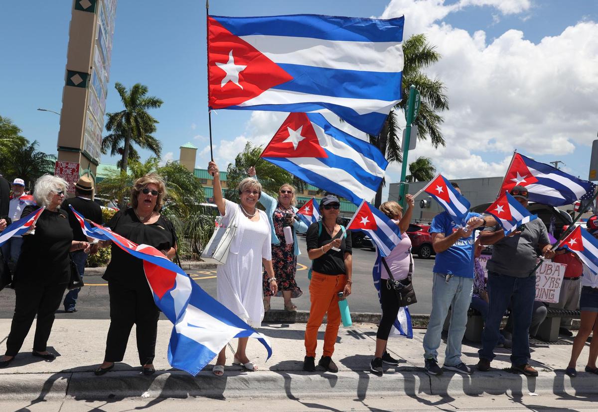 Christina María Rodríguez Benton, vestida blanco, ondea una bandera durante una distribución de banderas cubanas en La Carreta de la Calle 40, este lunes 11 de julio de 2022. La Asamblea de la Resistencia Cubana realizó una serie de actividades para conmemorar el primer aniversario de las protestas masivas del 11 de julio en Cuba.
