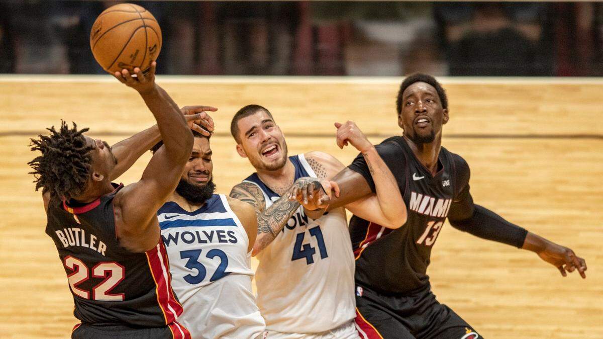 El delantero de los Heat Jimmy Butler (22) tira a la canasta mientras el pívot de los jugadores de los Timberwolves Karl-Anthony Towns (32) y Juancho Hernangomez (41) defienden al centro del Heat Bam Adebayo (13) en el AmericanAirlines Arena en Miami el viernes 7 de mayo de 2021.