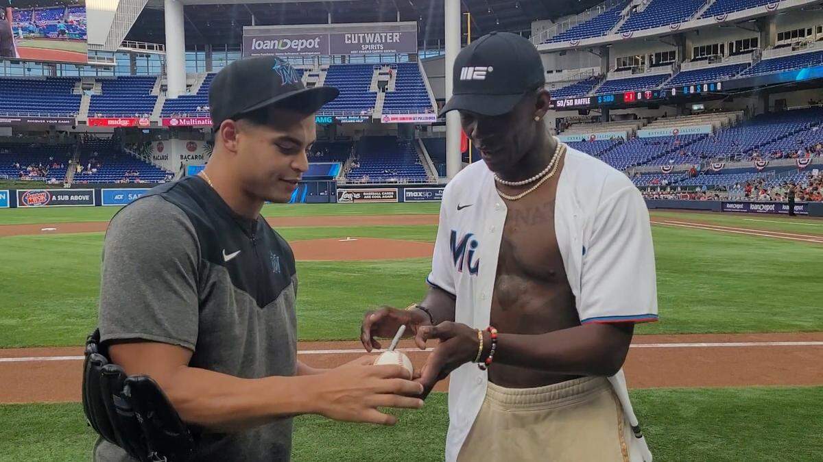 Jesús Luzardo (izq.) le firma una pelota a Israel Adesanya.