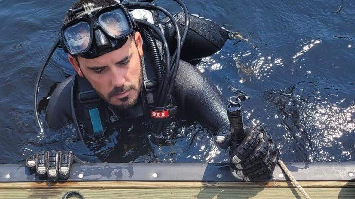 Un buzo del equipo del Departamento de Policía de de St. Johns County, Florida, observa el Rolex tras recuperarlo del arroyo el miércoles 22 de junio de 2022.
