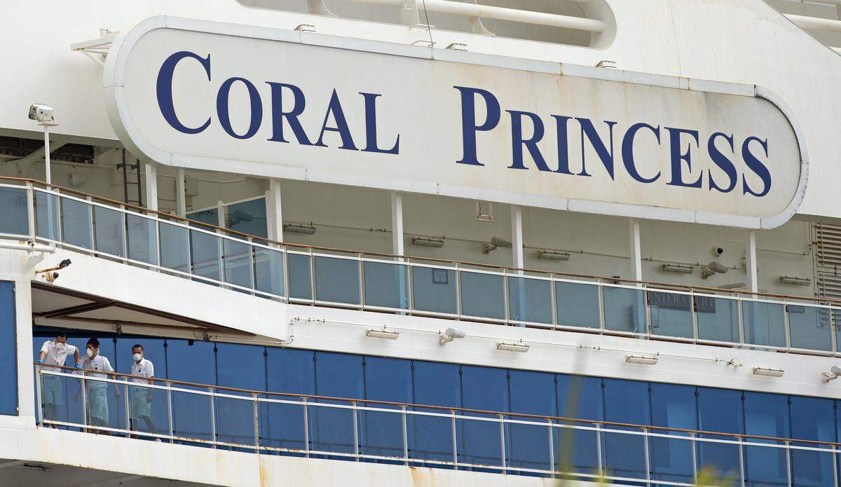 Los miembros de la tripulación del crucero Coral Princess miran desde su balcón hacia PortMiami el domingo 5 de abril de 2020 en Miami.
