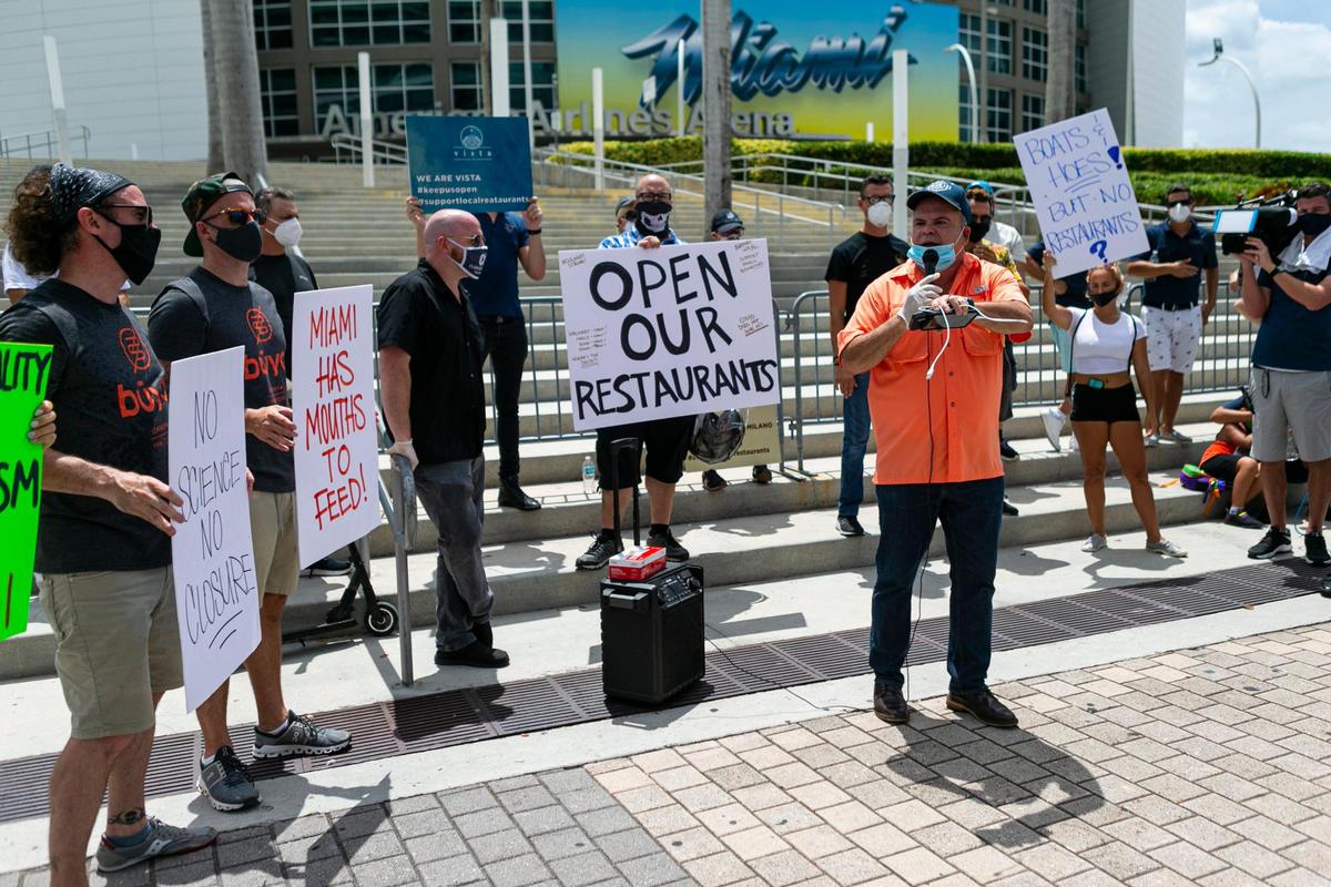 Evelio Medina (der.), presidente de la Cámara de Comercio del Downtown Miami y Brickell habla a los manifestantes y pide la renuncia del alcalde Giménez en la protesta de empleados y propietarios de restaurantes.