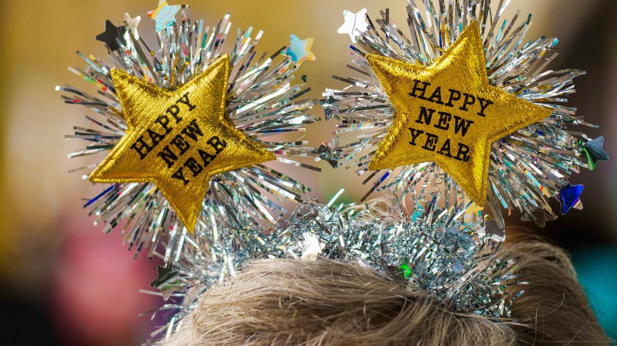 Una mujer recibe el 2024 con un tocado a juego con la inscripción “Feliz Año Nuevo” en el centro de la ciudad de Mainz, Rhineland, Alemania.