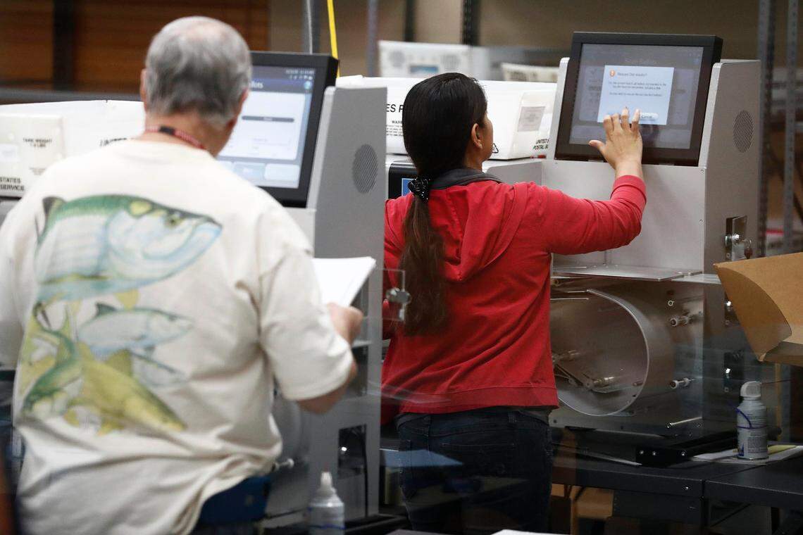 Broward County election staffers run ballots through tabulating machines on Nov. 11, 2018.