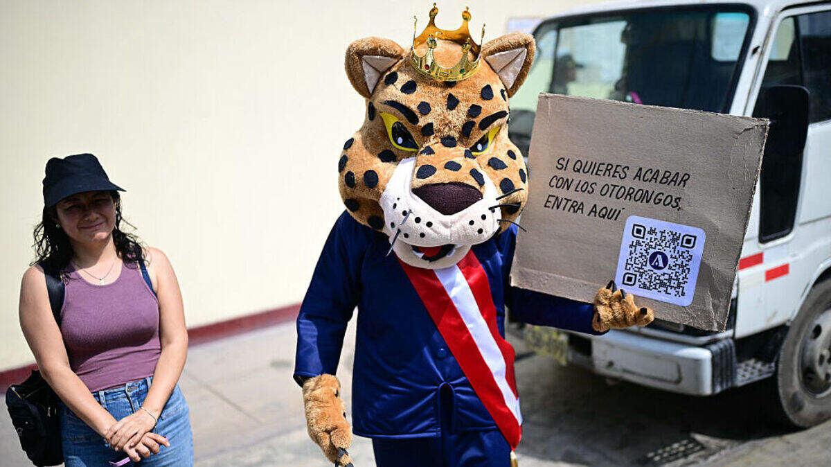 Un hombre sostiene un cartel que dice: “Si quieres acabar con los ‘otorongos’, haz clic aquí” —“otorongo” (término quechua para jaguar) es una expresión coloquial utilizada para referirse a miembros del Congreso o funcionarios de alto rango que actúan de manera poco ética o se protegen mutuamente para eludir la rendición de cuentas—, durante las elecciones presidenciales celebradas en Lima, el domingo 12 de abril de 2026.