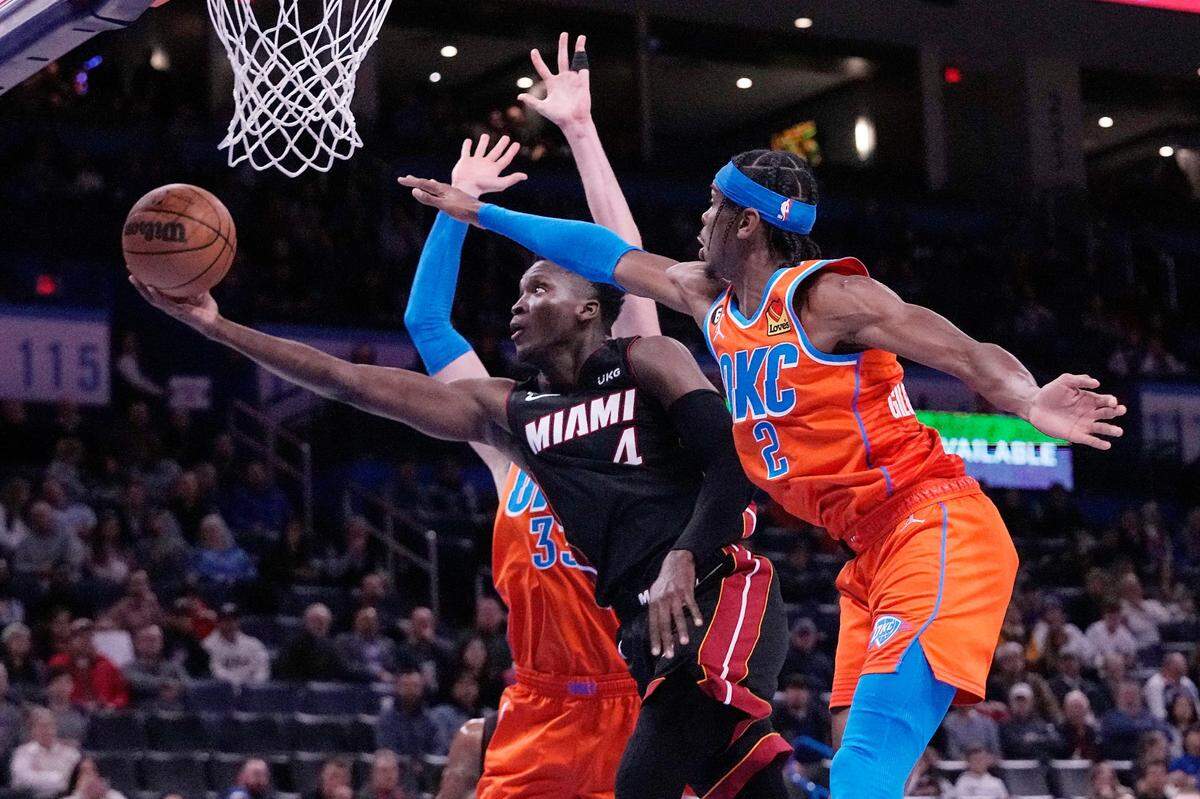 El escolta del Heat de Miami Victor Oladipo entra al aro ante la marca de Mike Muscala (izq.) y Shai Gilgeous-Alexander, del Thunder, en el partido celebrado el 14 de diciembre de 2022 en Oklahoma.