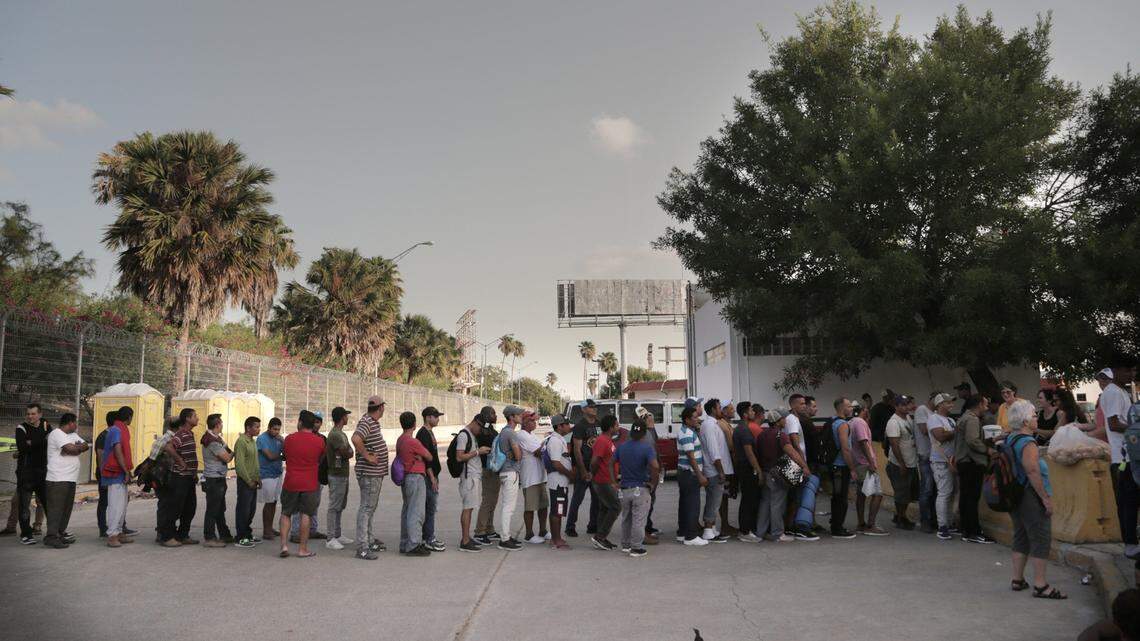 Los migrantes hacen fila para comer en un campamento ubicado en el lado de Matamoros, México, del Puente Internacional que conecta Matamoros con Brownsville, Texas. La iglesia y las organizaciones voluntarias en Brownsville llevan el agua y los alimentos para los migrantes en el lado mexicano de la frontera mientras esperan que se procesen sus solicitudes de asilo.