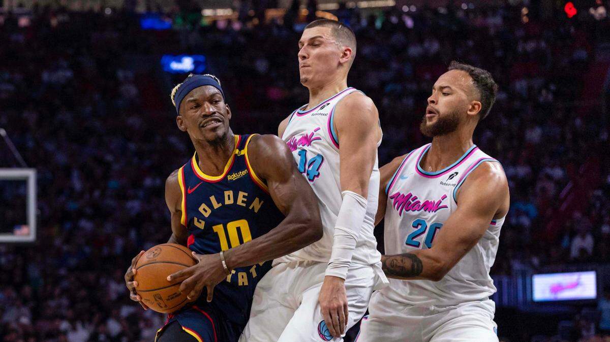 El jugador de los Warriors de Golden State Jimmy Butler (izq.) trata de pasar la marca de Tyler Herro (#14) y Kyle Anderson, del Heat, en el partido celebrado el 25 de marzo de 2025 en Miami.