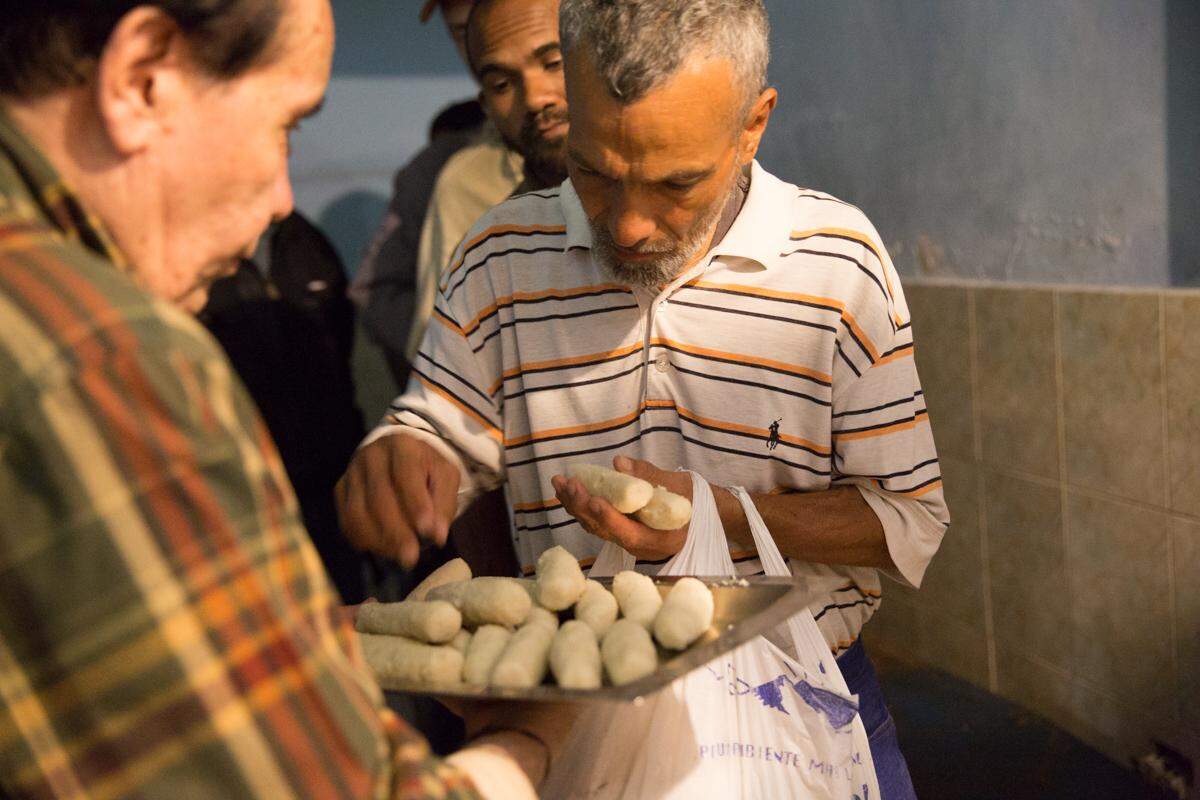 Cuando la sopa se acaba en la Casa de María, Benito Prieto (izquierda) sirve bollitos hechos de harina de maíz.  “La idea es que nadie se vaya sin comer nada. Y mañana podrán comer sopa”.