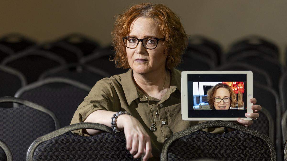 La pastora Jennifer LeClaire sostiene una tableta que muestra una imagen de un video falso de ella misma que circuló en línea y fue utilizado para estafar a sus feligreses.