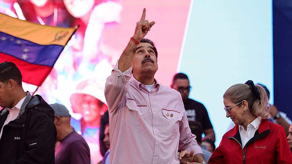 CARACAS, VENEZUELA - DECEMBER 1: President Nicolas Maduro of Venezuela makes a gesture skywards alongside his wife and First Lady Cilia Flores during a protest to show him support on December 1, 2025 in Caracas, Venezuela. Supporters gathered at Miraflores to show support and to be part of the swearing-in of the 'Integral Bolivarian Community Commands.' (Photo by Jesus Vargas/Getty Images)