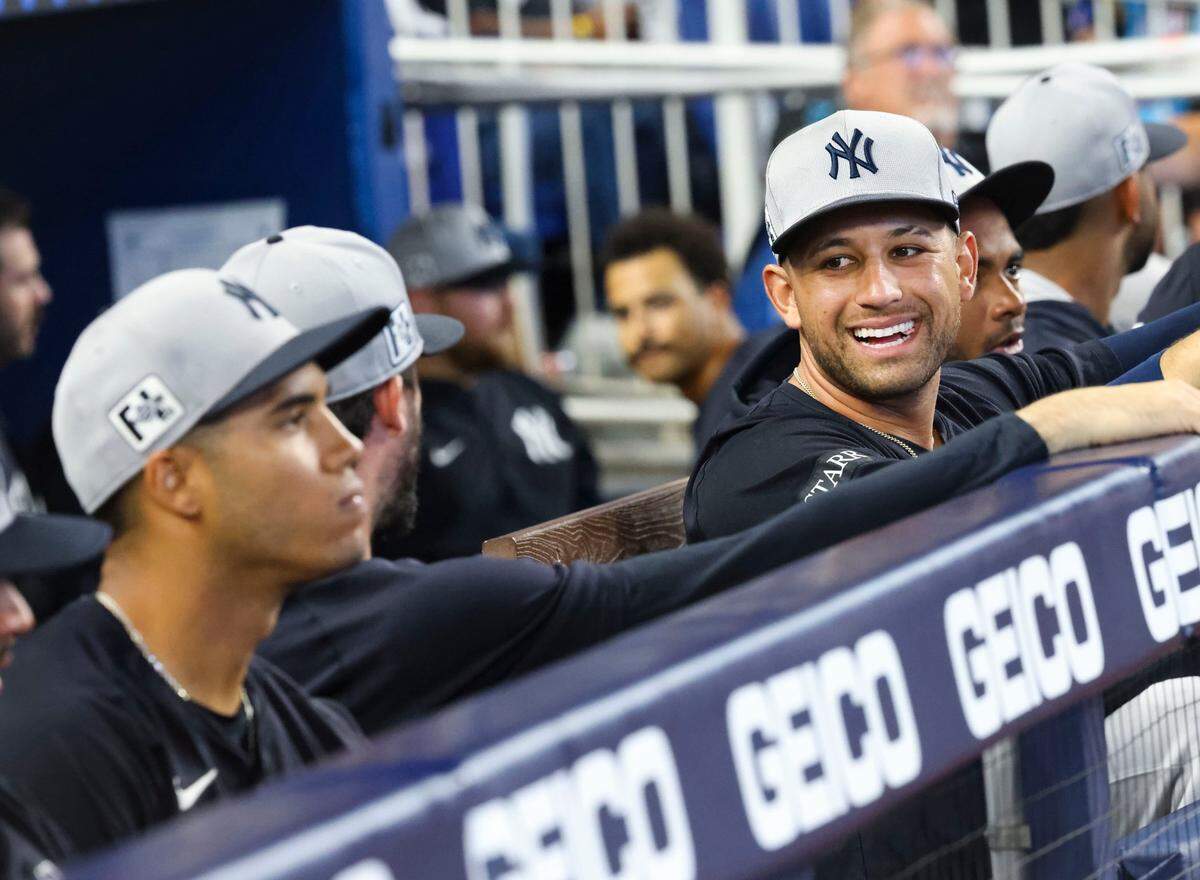 El receptor de los Yankees de Nueva York JC Escarra (der.) sonríe en el dugout antes del partido de exhibición ante los Marlins, celebrado el 25 de marzo de 2025 en Miami.