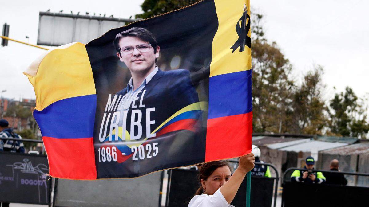 Una mujer sostiene una bandera de Colombia con la imagen de Miguel Uribe Turbay durante el funeral del senador y precandidato presidencial, el 13 de agosto de 2025, en Bogotá.