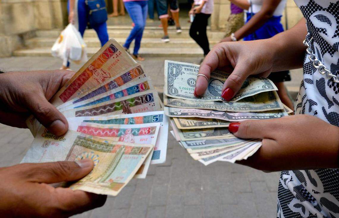 En esta foto de archivo del 10 de diciembre de 2019, cubanos muestran billetes de dólar y CUC en una calle de La Habana.