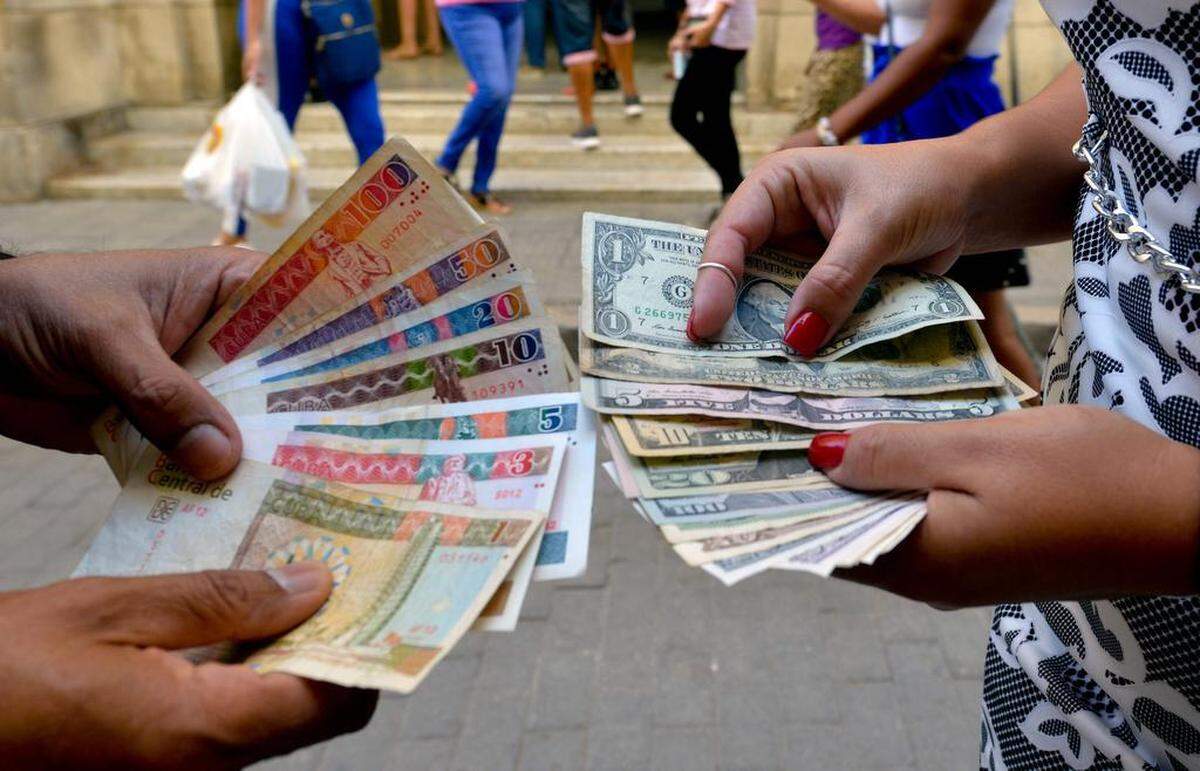 En esta foto de archivo del 10 de diciembre de 2019, cubanos muestran billetes de dólar y CUC en una calle de La Habana.