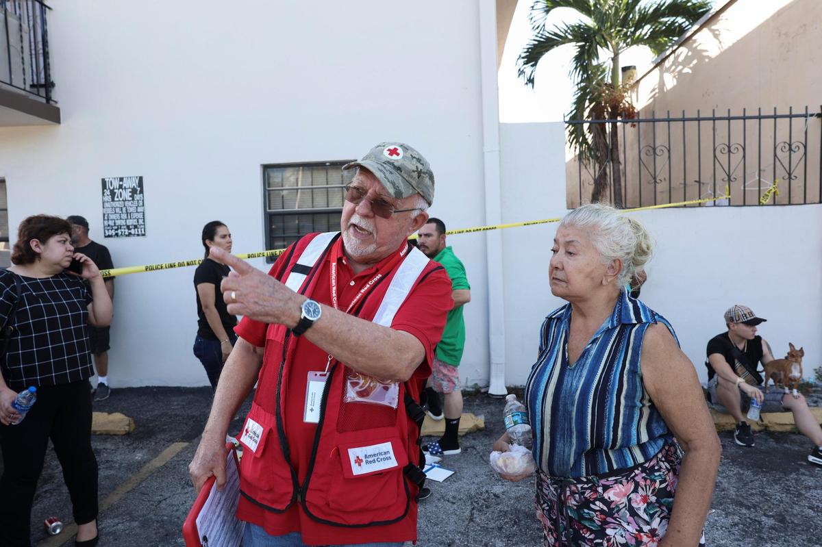 Pete Suárez, a la izquierda, voluntario del equipo de Respuesta a Desastres de la Cruz Roja, habla con los residentes mientras esperan respuestas después de que un pasillo del segundo piso se derrumbara esta mañana. El edificio de Palm Avenue, en Hialeah, se declaró “inseguro” este lunes 31 de octubre de 2022.
