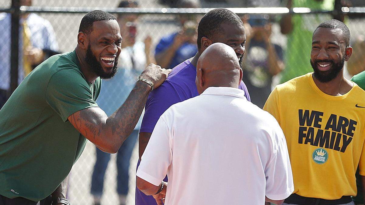 LeBron James (izq.) se ríe con el entrenador Dru Joyce y dos ex compañeros de equipo antes de jugar contra estudiantes de su escuela I Promise, el 14 de agosto de 2019, en Akron, Ohio.