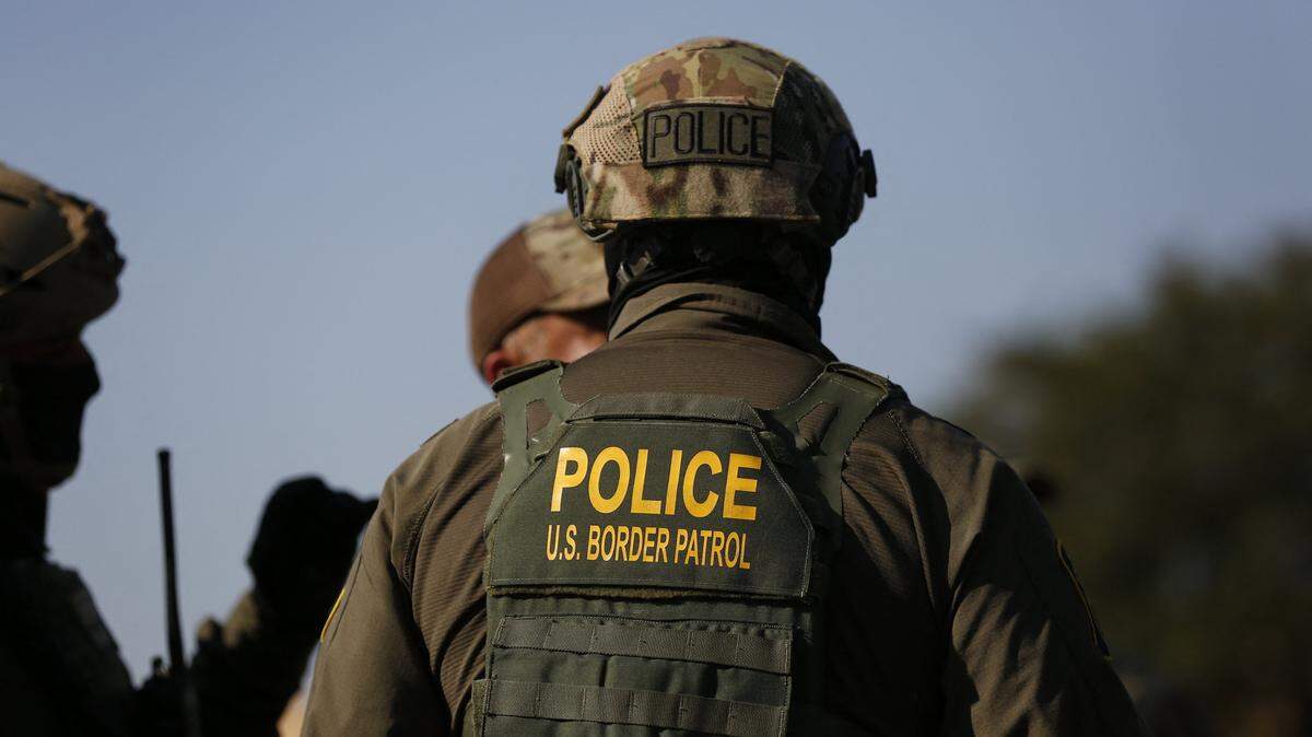 US Customs and Border Protection (CBP) agents stand guard as hundreds of protesters gather near an Immigration and Customs Enforcement (ICE) facility opposing the detention of undocumented immigrants following President Donald Trump's order to increase federal presence and step up immigration enforcement through the Department of Homeland Security in Broadview, Illinois, on October 3, 2025. US President Donald Trump, who campaigned on a pledge to deport large numbers of migrants, has encouraged authorities to be more aggressive as he seeks to hit his widely reported target of one million deportations annually. (Photo by OCTAVIO JONES / AFP) (Photo by OCTAVIO JONES/AFP via Getty Images)