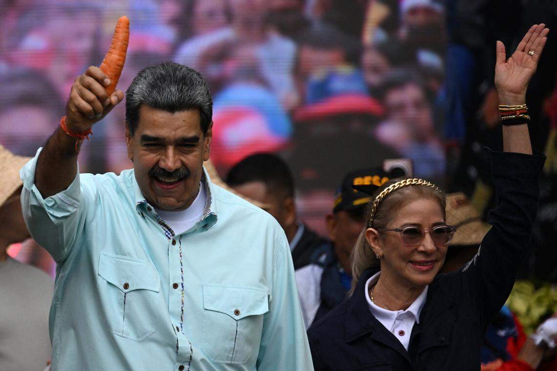Venezuela's President Nicolas Maduro holds a carrot as he arrives with First Lady Cilia Flores at a rally marking the anniversary of the Battle of Santa Ines, in Caracas on December 10, 2025. (Photo by Federico PARRA / AFP via Getty Images)